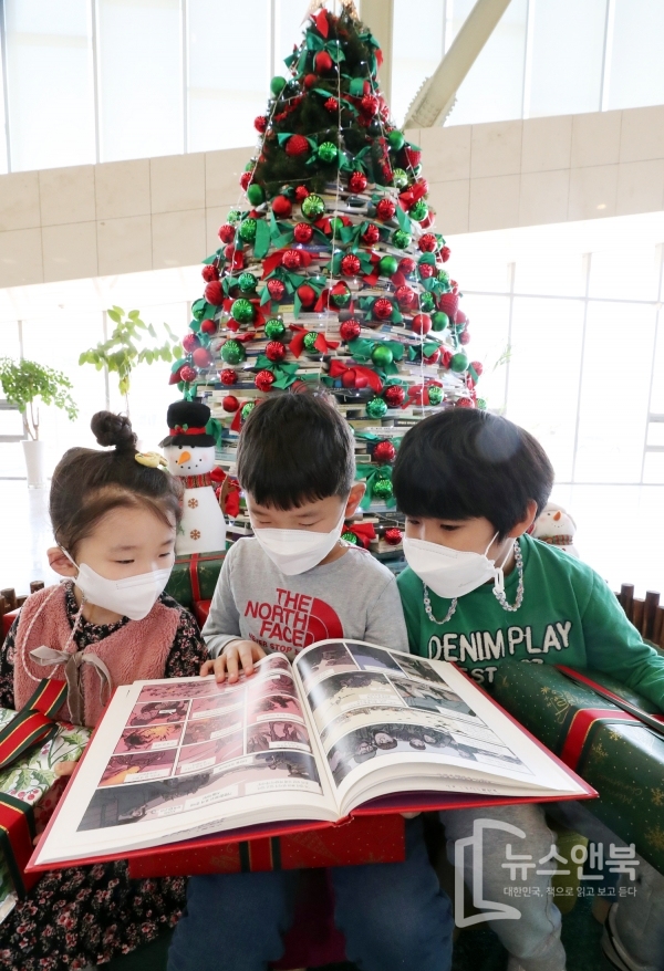 세종시 어진동 국립세종도서관 로비에 전시된 크리스마스 책 트리 앞에서 어린이들이 책을 읽고 있다. 전우용 기자